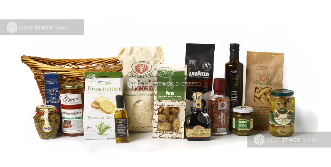 Multiple Italian food products on a white background with a basket