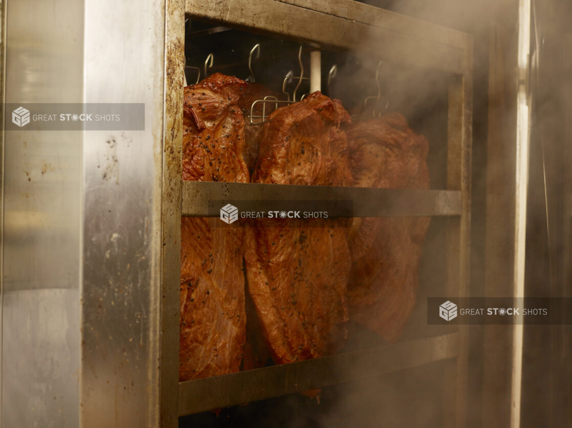 Pastrami hanging in a smoker in a restaurant