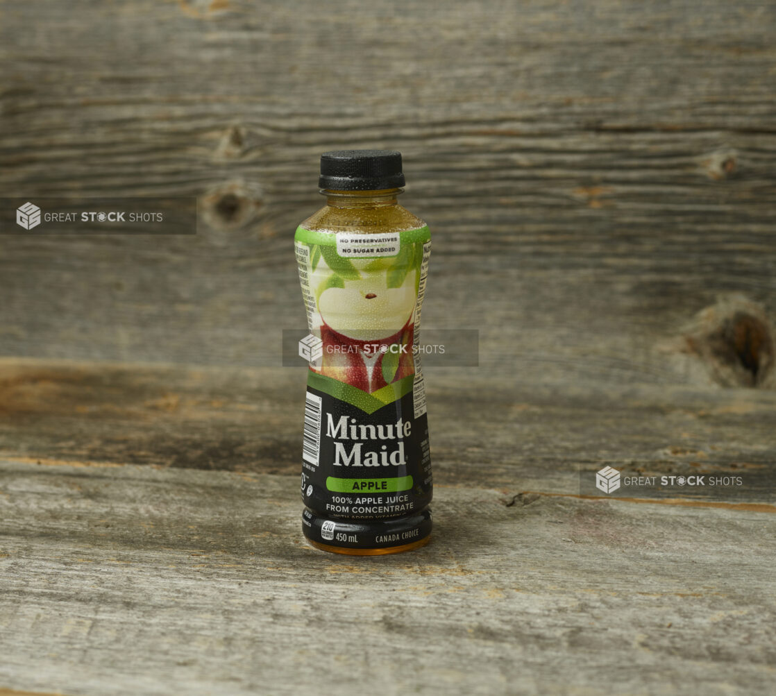 Minute Maid apple juice in a plastic bottle on an aged wooden table and background straight on view