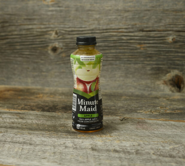 Minute Maid apple juice in a plastic bottle on an aged wooden table and background straight on view