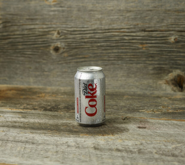 Diet Coke can on a wooden table with a wooden background with a straight on view
