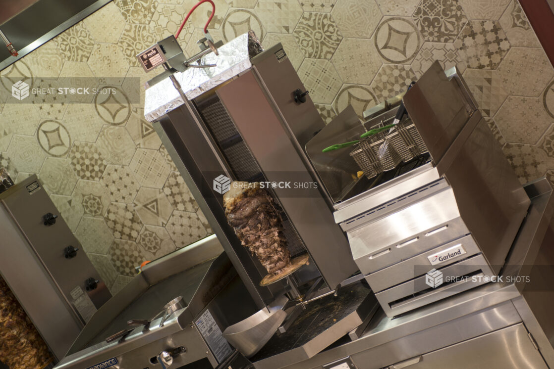 Restaurant equipment, vertical broiler, flat top, deep fryer on counter with meat and chicken shawarma