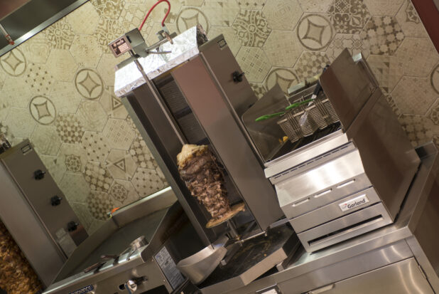 Restaurant equipment, vertical broiler, flat top, deep fryer on counter with meat and chicken shawarma