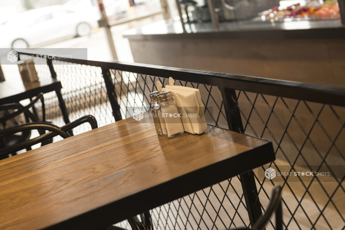 Restaurant table with wood tabletop, salt and pepper shakers, and napkin holder