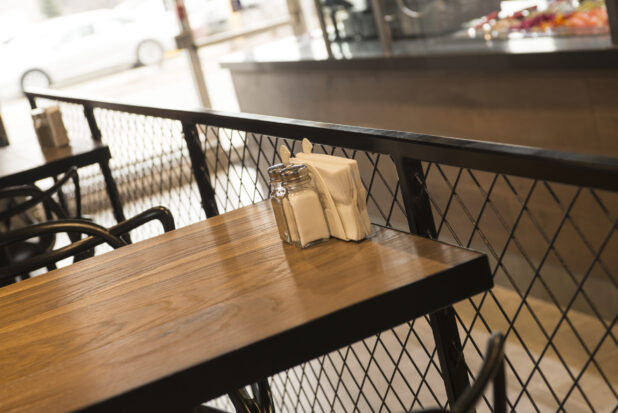 Restaurant table with wood tabletop, salt and pepper shakers, and napkin holder