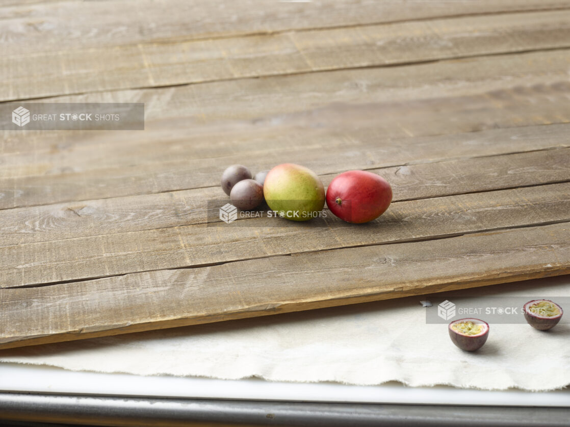 Whole mango and passionfruit on aged wooden planks