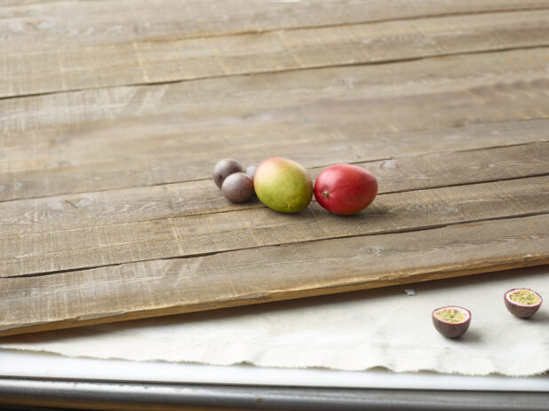 Whole mango and passionfruit on aged wooden planks