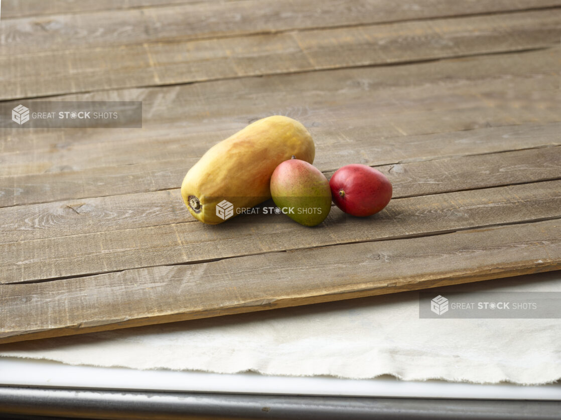 Whole papaya and mango on aged wooden planks