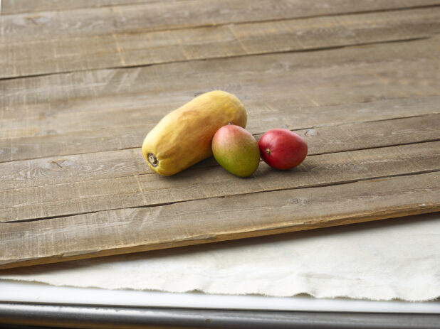 Whole papaya and mango on aged wooden planks