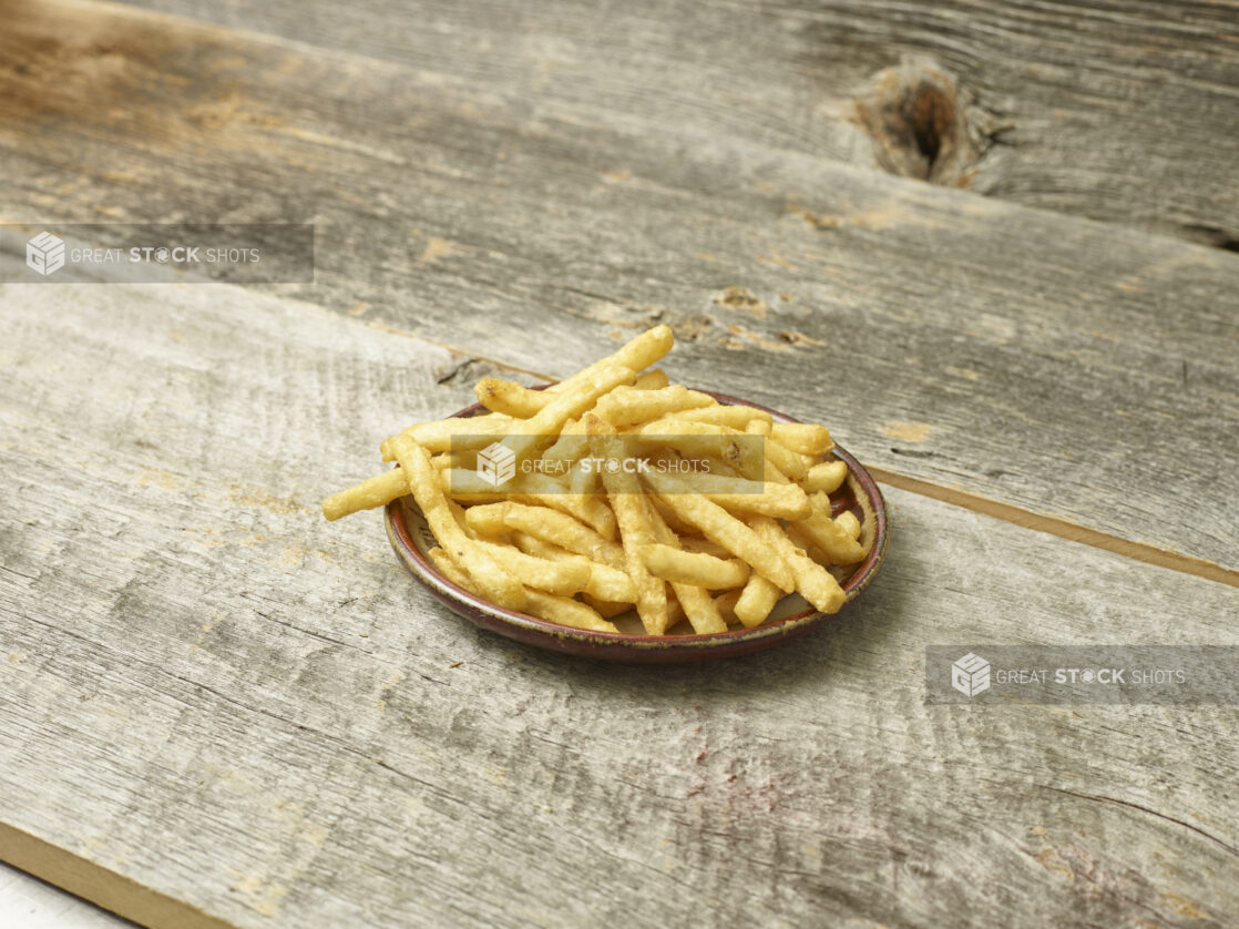 French fries on a plate on an aged wooden table