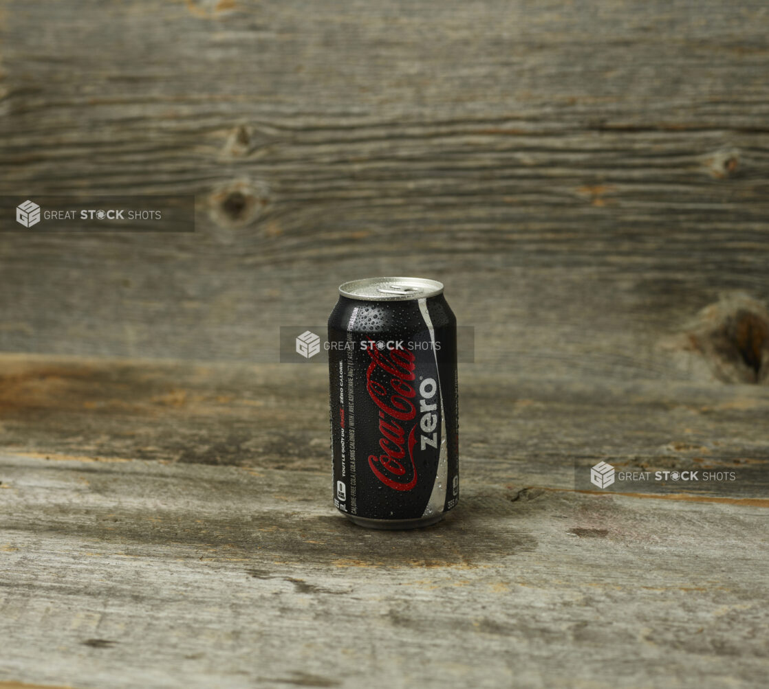 Coke Zero can on a wooden table with a wooden background and a straight on view