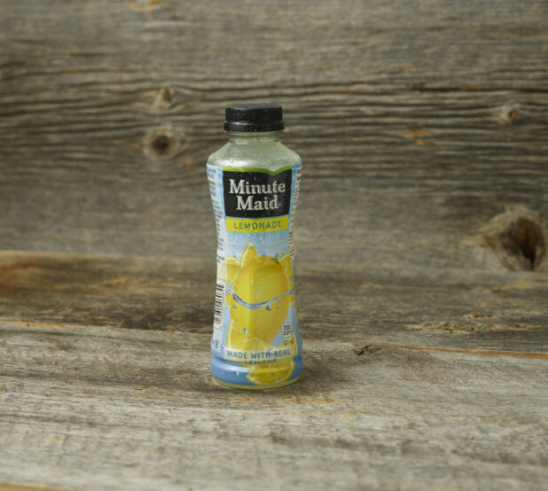 Minute Maid Lemonade in a plastic bottle on a wooden table with a wooden background and a straight on view