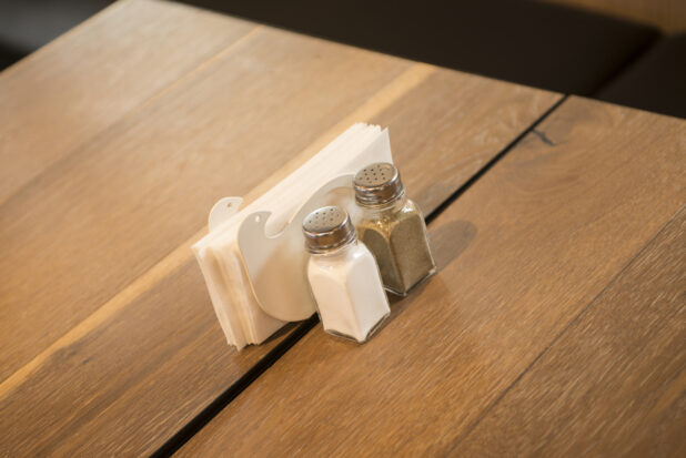 Salt and pepper shaker and napkin holder on a wooden restaurant table