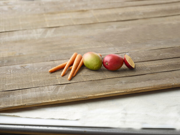 Whole carrots and mangoes on wooden planks
