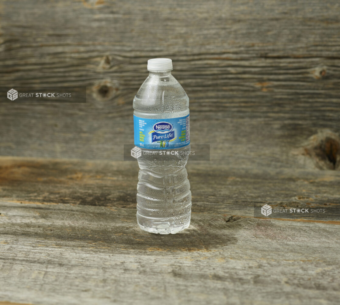 Nestle Pure Life water in a plastic bottle on a wooden table with a wooden background and straight on view