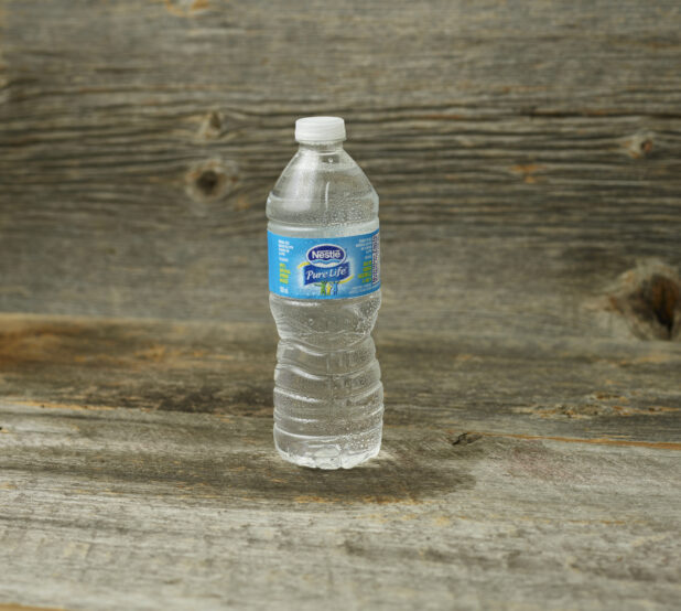 Nestle Pure Life water in a plastic bottle on a wooden table with a wooden background and straight on view