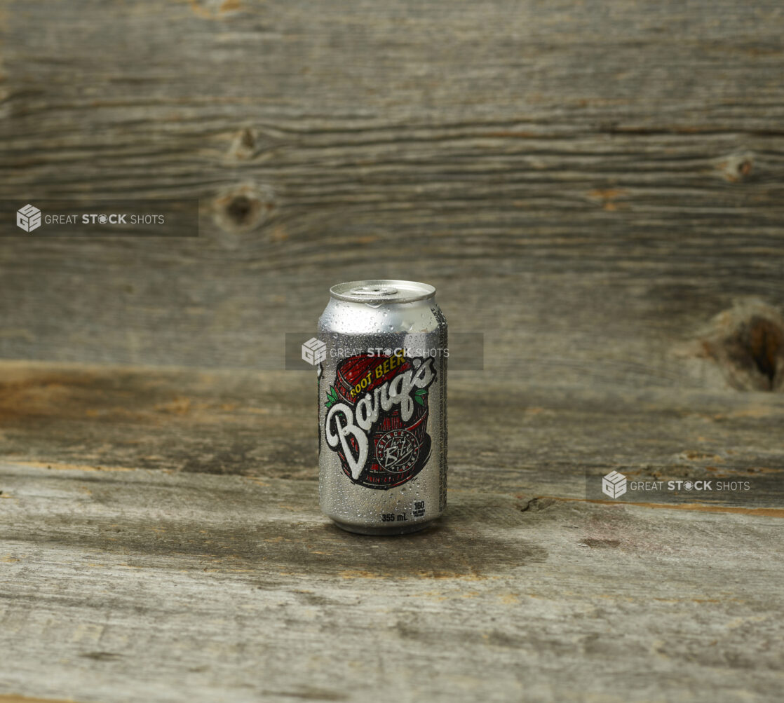 Barq's root beer in a can on a wooden table with a wooden background and straight on view