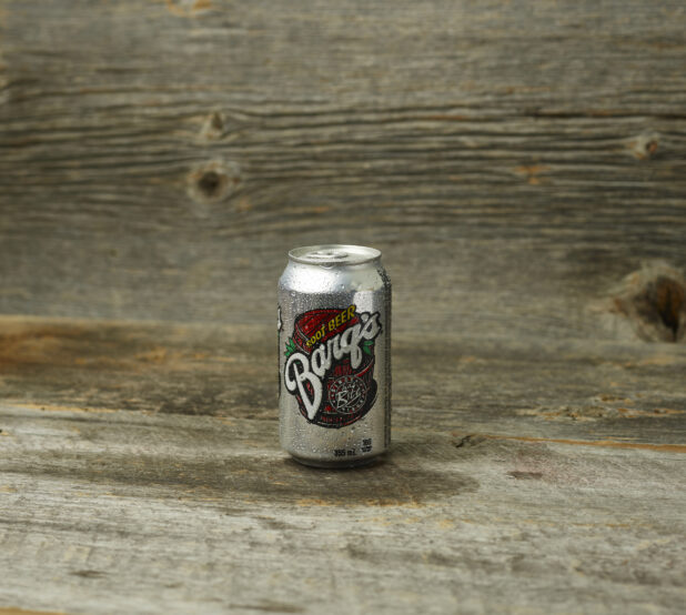 Barq's root beer in a can on a wooden table with a wooden background and straight on view