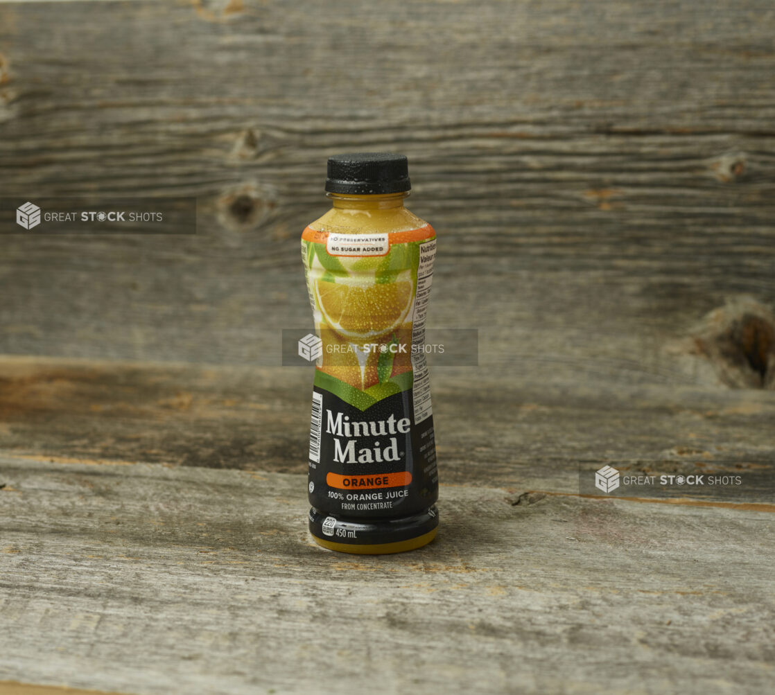 Minute Maid orange juice on a wooden table with a wooden background and a straight on view