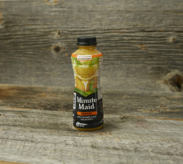 Minute Maid orange juice on a wooden table with a wooden background and a straight on view