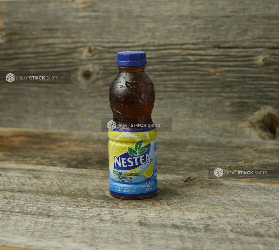 Nestea Natural Lemon iced tea in a plastic bottle on a wooden table with a wooden background and straight on view