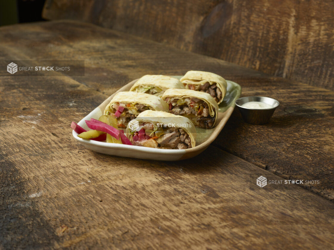 Platter of shawarma bites on a wooden table with wooden background