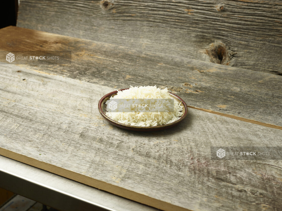 Cooked rice on a plate on a wooden background on a slight bias, rustic wood background