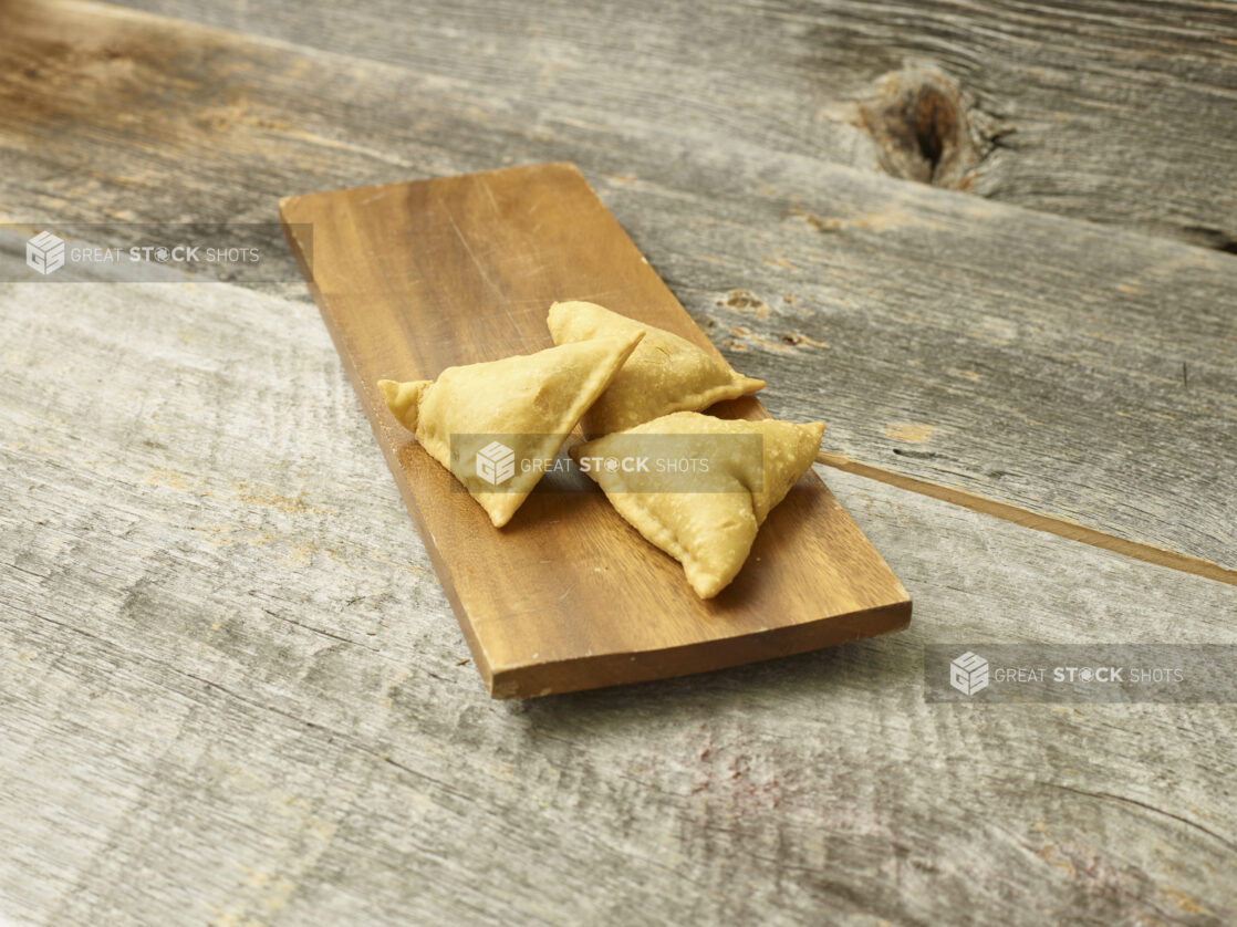 Samosa appetizer on a wooden platter on a wooden background