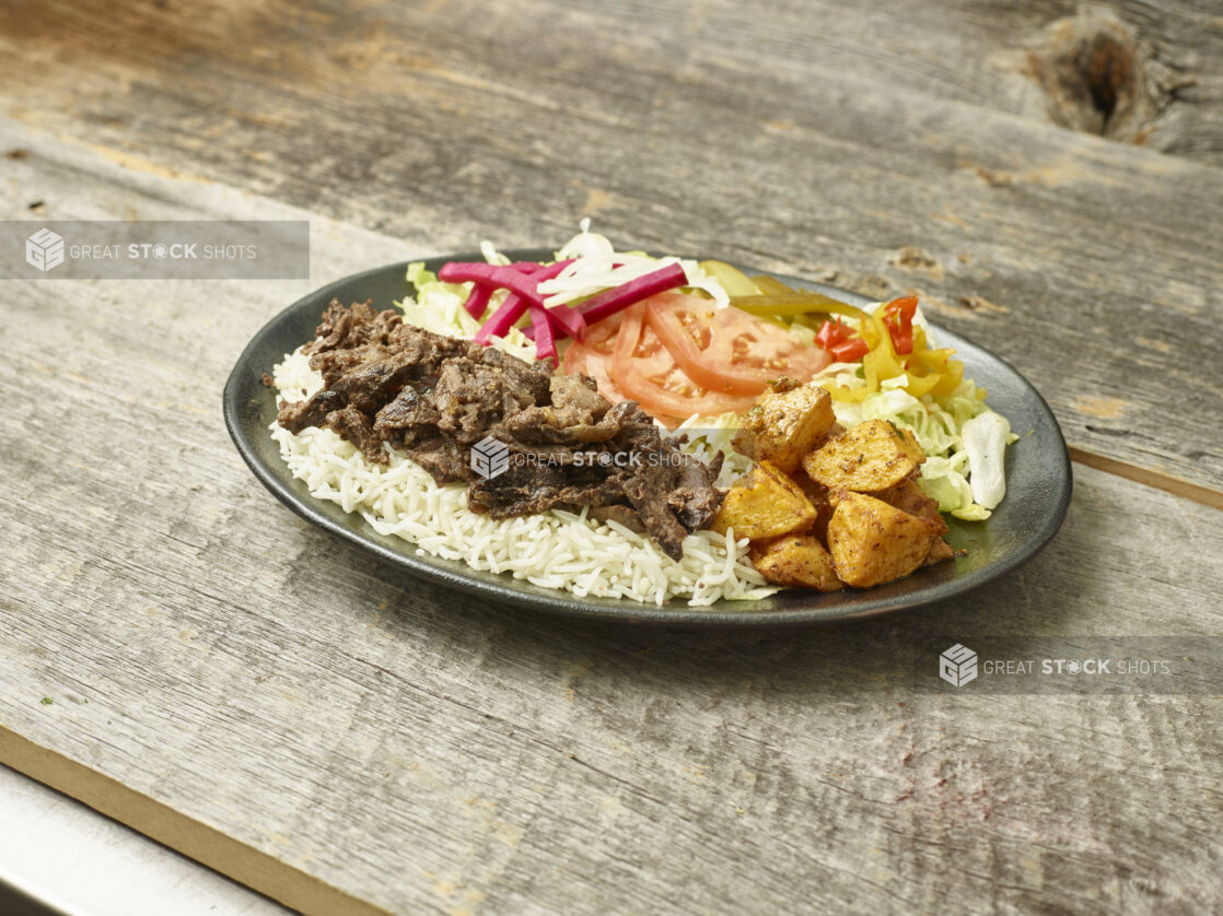 Beef shawarma dinner on a plate on a wooden background/table shot on an angle