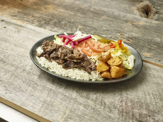 Beef shawarma dinner on a plate on a wooden background/table shot on an angle