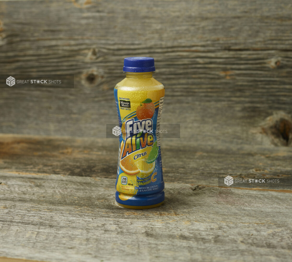 Five Alive juice in a plastic bottle on a wooden table with a wooden background and a straight on view