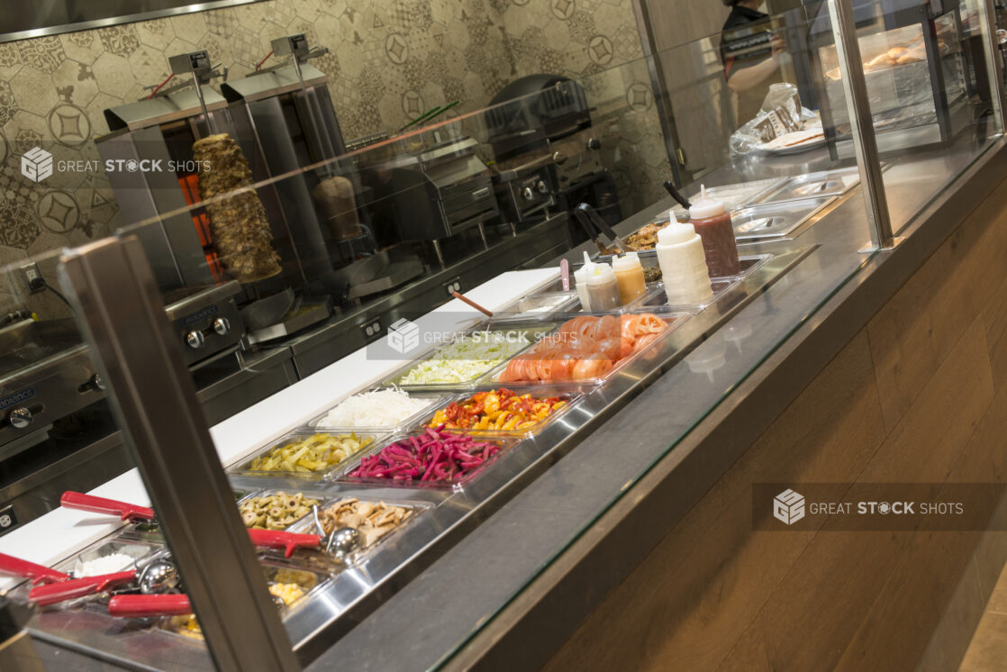 Middle Eastern counter with Shawarma toppings and vertical broiler in background