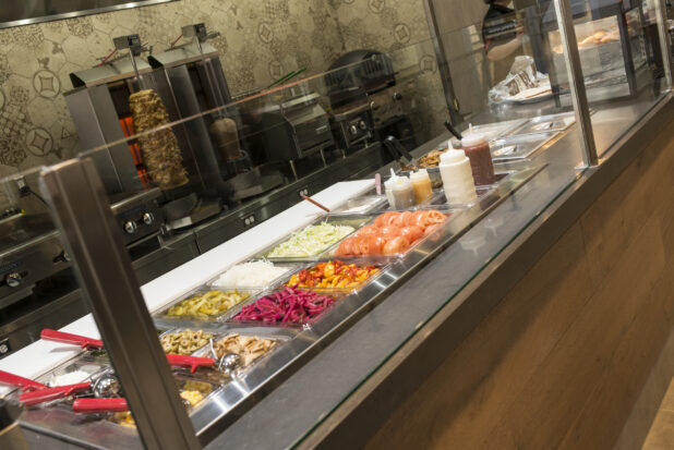 Middle Eastern counter with Shawarma toppings and vertical broiler in background