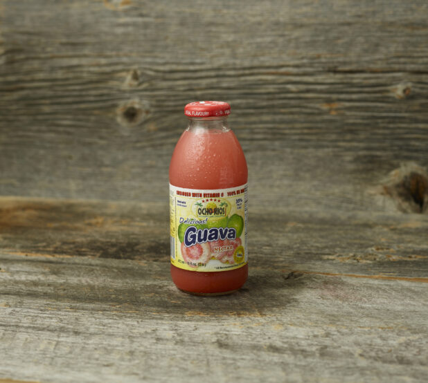 Guava juice in a bottle on a wooden table with a wooden background and a straight on view