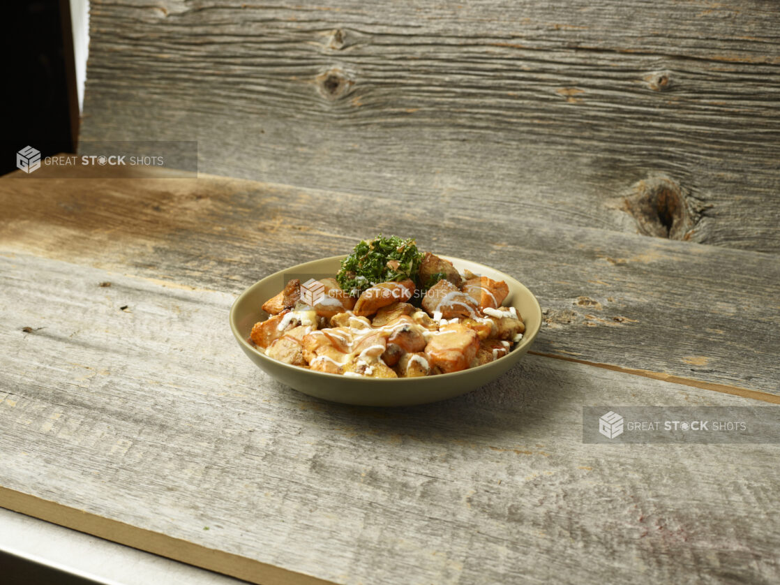 Chicken shawarma potato bowl with parsley on a wooden table with a wooden background