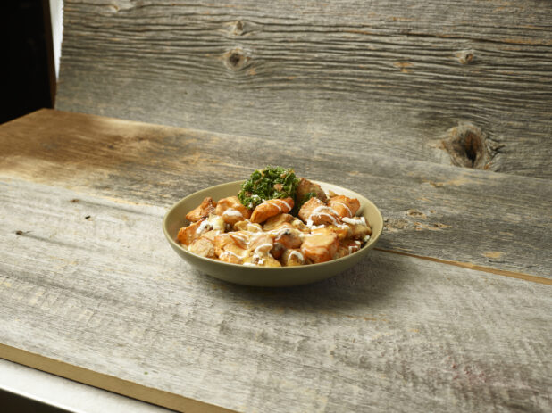 Chicken shawarma potato bowl with parsley on a wooden table with a wooden background