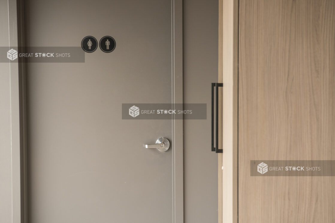 Unisex bathroom door with side view of a cupboard