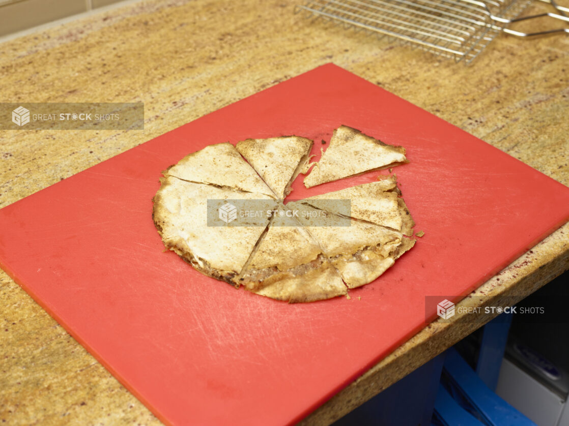 Lahmajeen/Middle Eastern Pizza sliced on red cutting board top/side view on a marble counter top