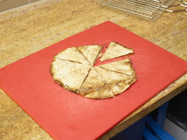 Lahmajeen/Middle Eastern Pizza sliced on red cutting board top/side view on a marble counter top