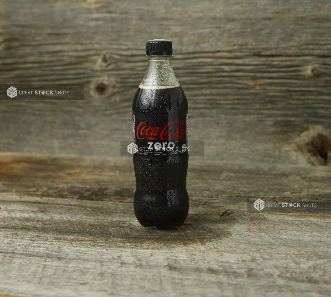 Coke Zero on a wooden table with a wooden background and a straight on view