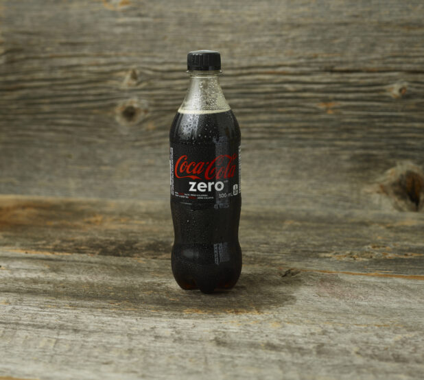 Coke Zero on a wooden table with a wooden background and a straight on view