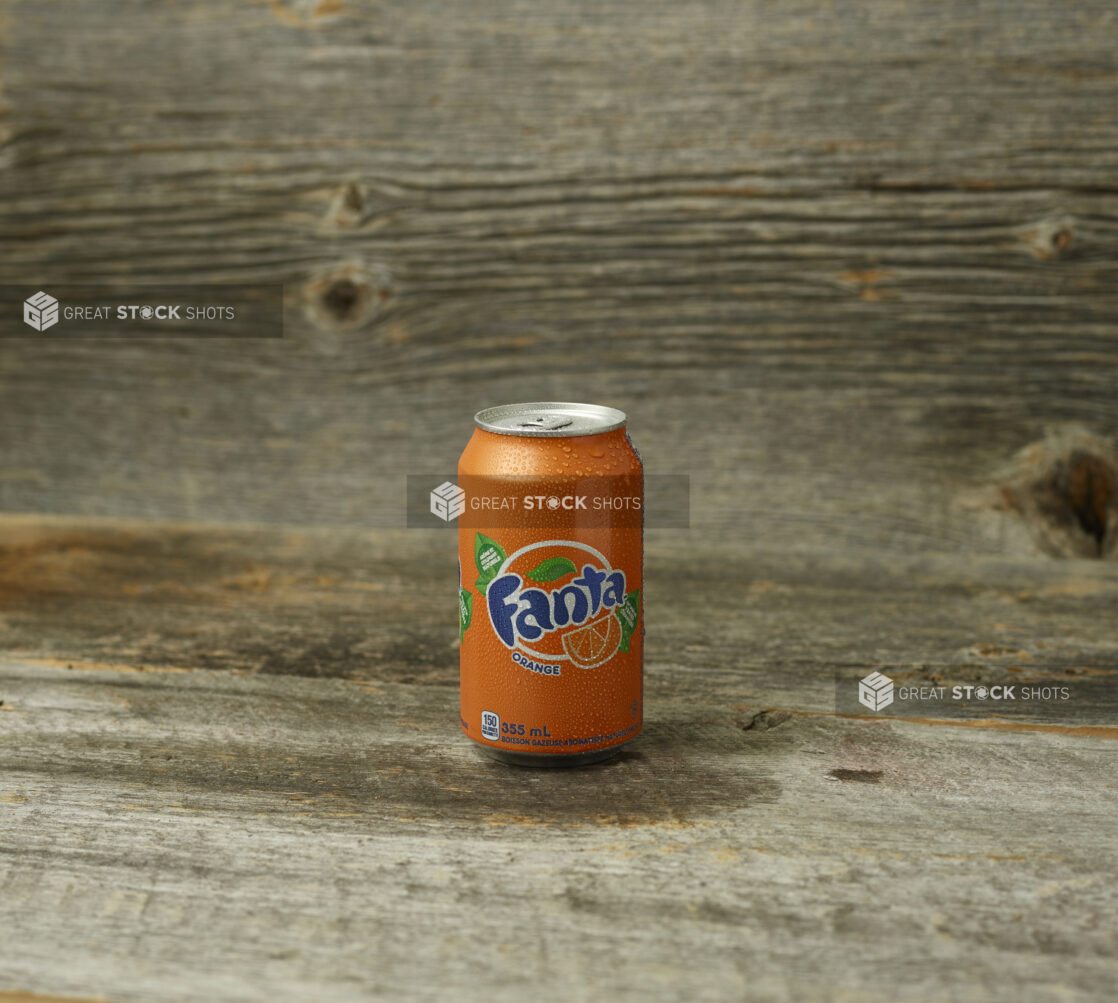 Fanta orange soda on a wooden table with a wooden background and a straight on view