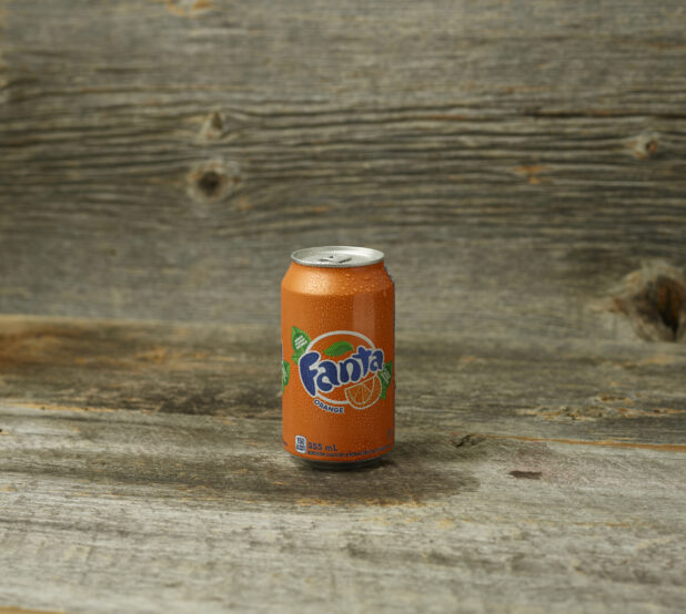 Fanta orange soda on a wooden table with a wooden background and a straight on view