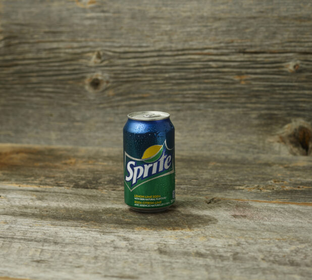 Can of Sprite on a wooden table with a wooden background and straight on view