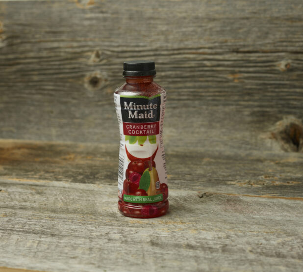 Minute Maid cranberry cocktail in a plastic bottle on a wooden table with a wooden background