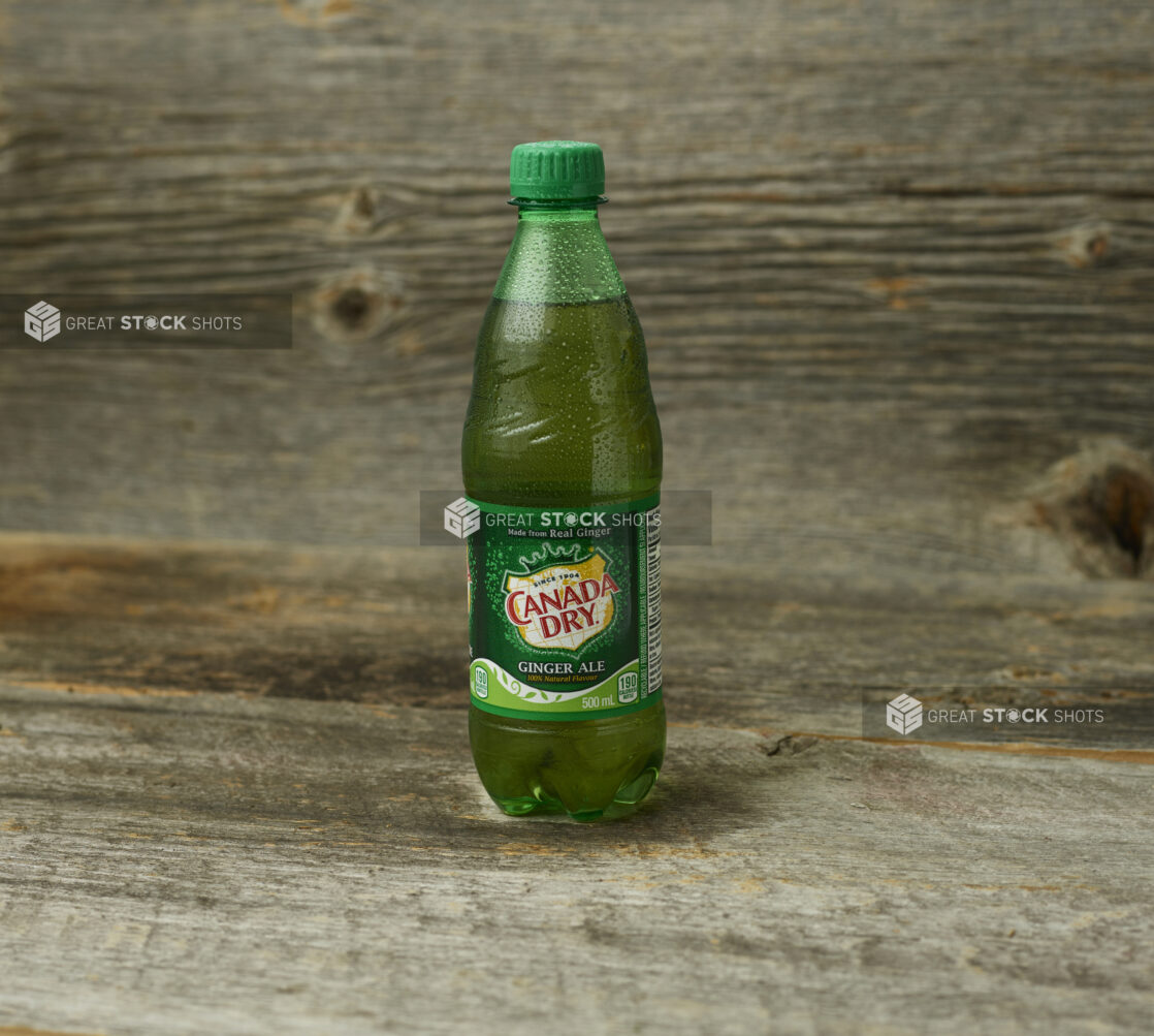 Canada Dry Gingerale in a plastic bottle on a wooden surface with wooden background