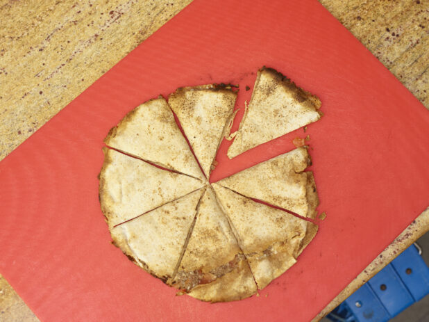 Overhead view of a Lahmajeen/Middle Eastern pizza on a red background