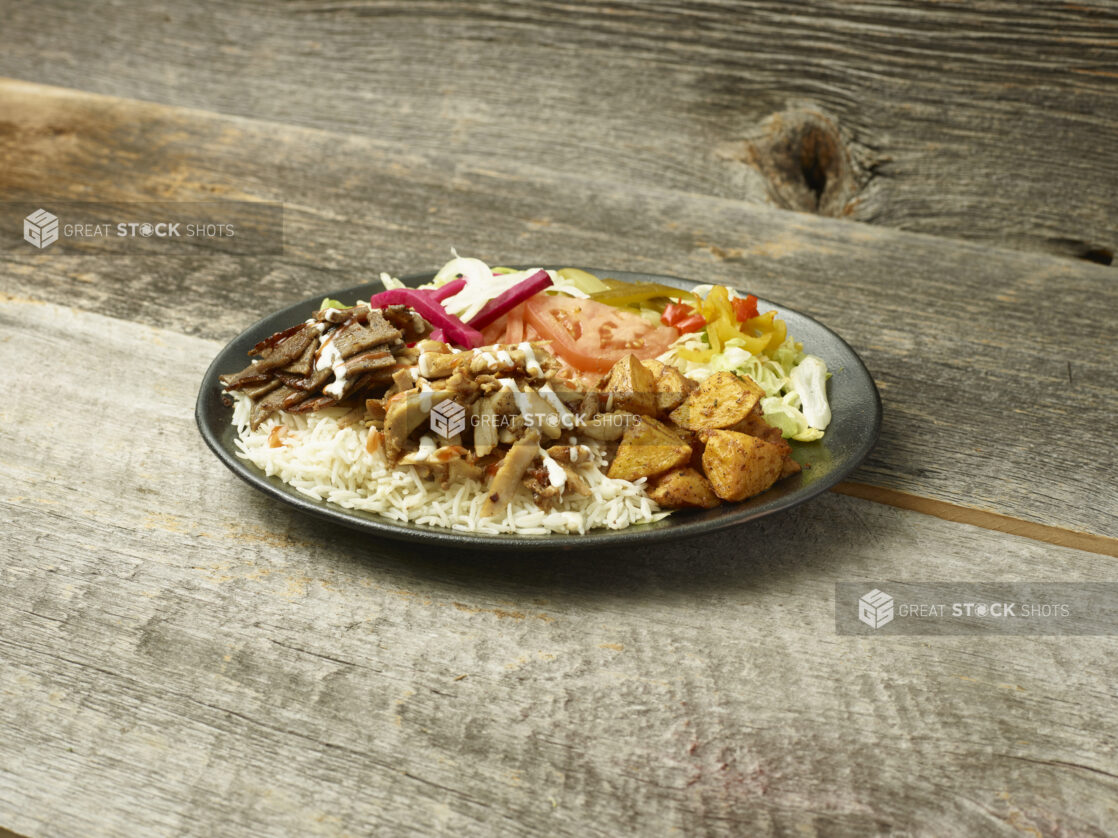 Middle eastern/Mediterranean chicken and beef meal on a plate on a wooden table