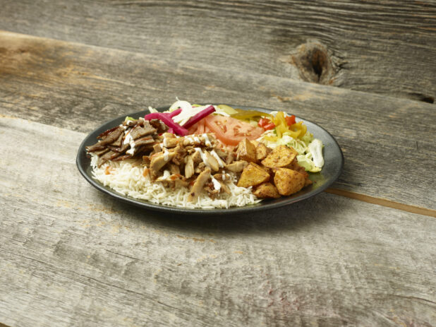 Middle eastern/Mediterranean chicken and beef meal on a plate on a wooden table