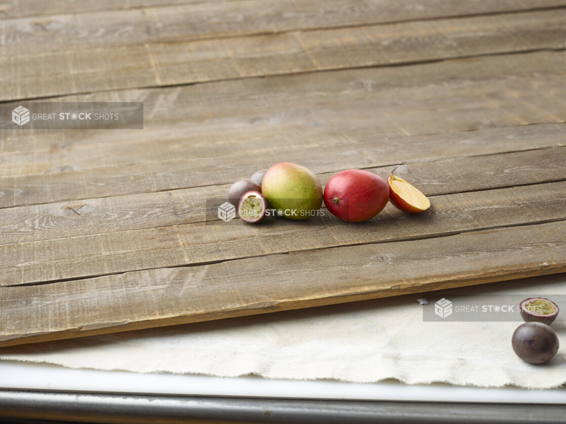 Sliced and whole mango and passionfruit on wooden planks